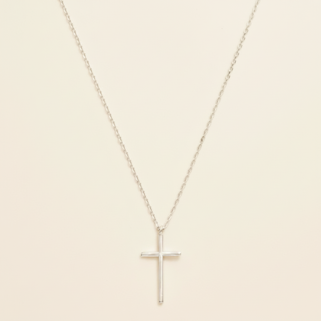 Silver dainty cross necklace on warm cream background