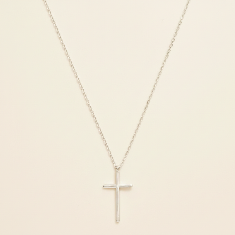 Silver dainty cross necklace on warm cream background